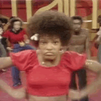 a woman in a red top is dancing in front of a group of people