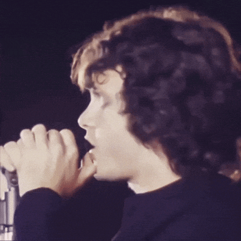 a man is singing into a microphone with his eyes closed