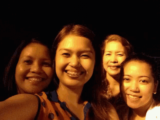 four women are posing for a picture together and smiling at the camera