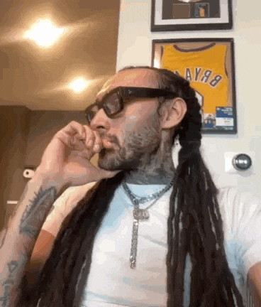 a man with dreadlocks wearing sunglasses and a white shirt