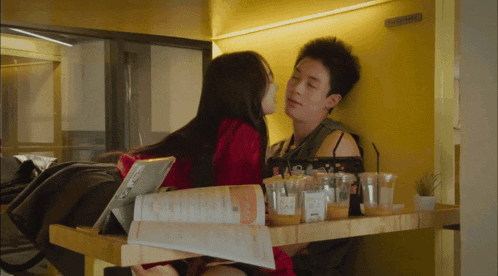 a woman kisses a man on the cheek in front of a yellow wall with a sign that says " please do not enter "