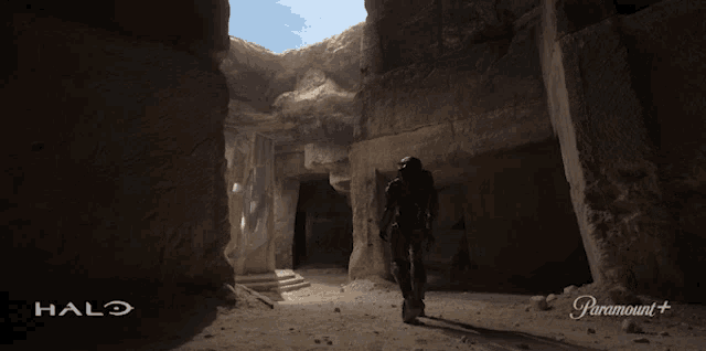 a man is walking through a cave with the halo logo on the bottom