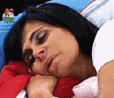 a woman is sleeping in a bed with her eyes closed and a snowman in the background
