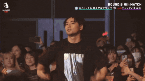 a man in a black shirt stands in front of a crowd with the words round 6 6th match on the bottom