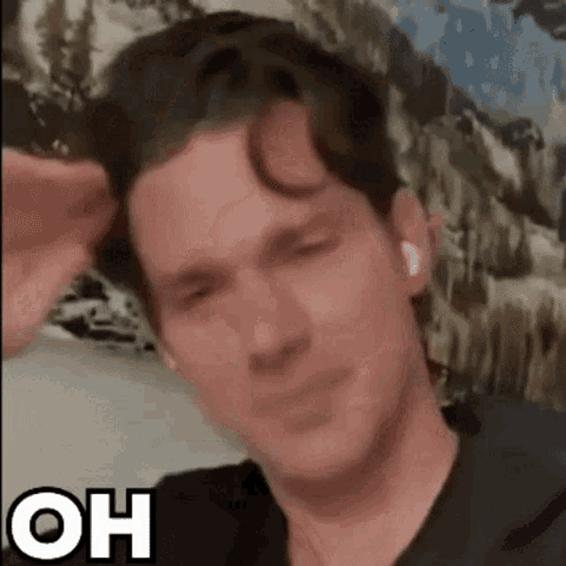 a man in a black shirt is making a funny face while wearing ear buds .