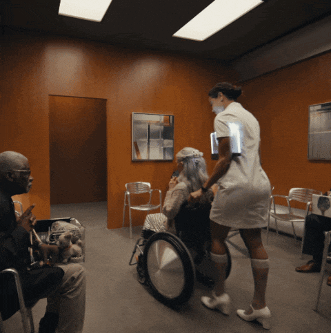 a woman in a wheelchair is being pushed by a nurse in a waiting room