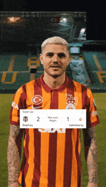a man in a striped shirt stands on a soccer field with a scoreboard behind him
