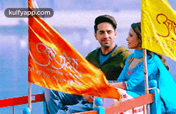 a man and woman are sitting on a boat with flags .