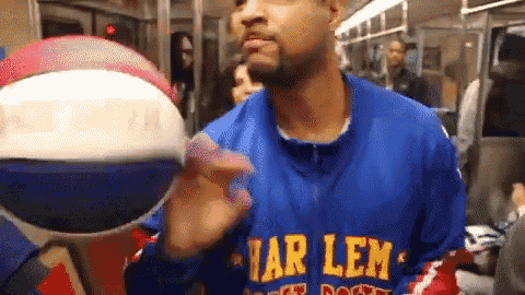 a man wearing a harlem globetrotters jersey holds a basketball in his hand