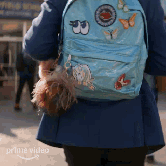 a person wearing a blue backpack with stickers on it and the word prime video on the bottom