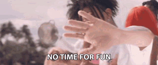 a man with dreadlocks is covering his face with his hands and the words `` no time for fun '' are written above him .