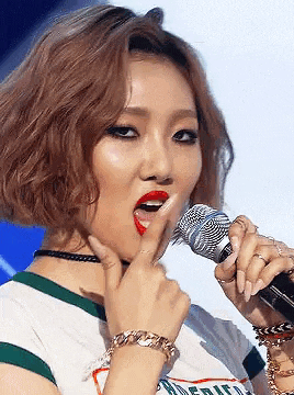 a woman is singing into a microphone while holding her finger to her mouth .