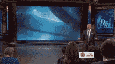 a man in a suit and tie stands in front of a large screen that says dr phil on it