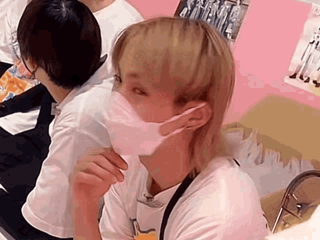 a woman wearing a face mask is sitting in a room with other people
