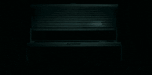 a dark room with a blue light shining through a blind