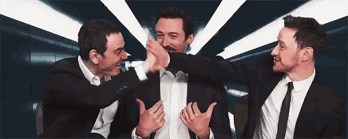 three men in suits and ties are sitting next to each other in a room .