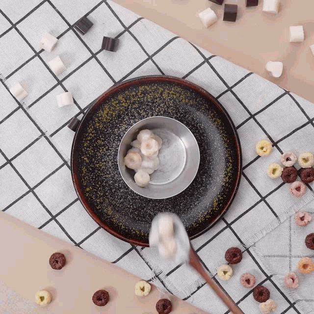 a bowl of marshmallows is being poured into a plate of cereal