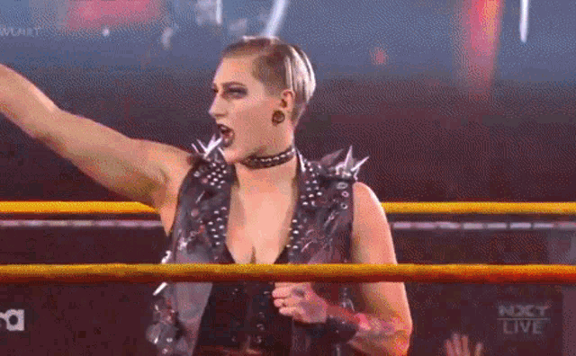 a woman is standing in a wrestling ring holding a microphone .