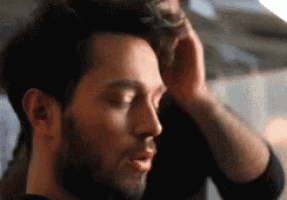 a close up of a man 's face with his eyes closed and his hand on his head