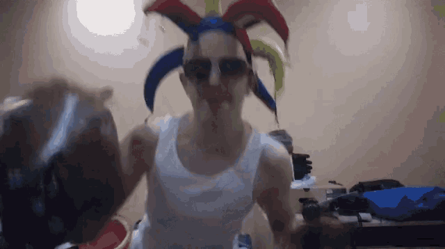 a man wearing a jester 's hat and sunglasses is holding a bottle of water .