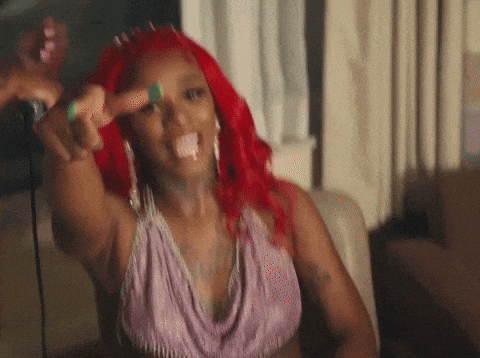 a woman with red hair is sticking her tongue out and giving the middle finger .