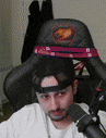 a man is sitting in a chair with a hat on his head and a microphone .