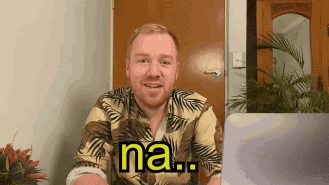 a man in a hawaiian shirt says na in front of a laptop