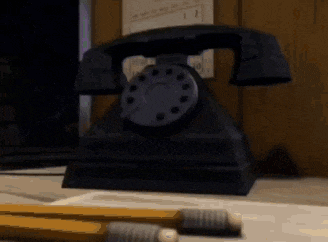 a black telephone is sitting on a desk next to pencils