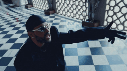 a man wearing glasses and a turban is pointing with his fingers