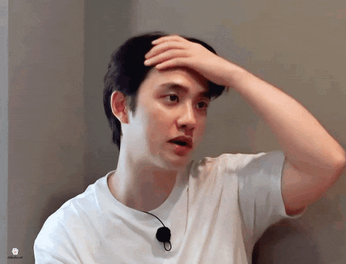 a man in a white shirt is holding his hand to his head