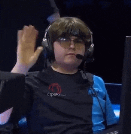 a man wearing headphones and glasses is giving a high five while sitting in front of a computer .