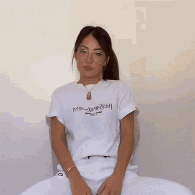 a woman wearing glasses and a white t-shirt that says ivbna on it