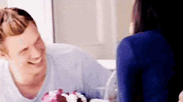 a man and a woman are sitting at a table with a cake on it .
