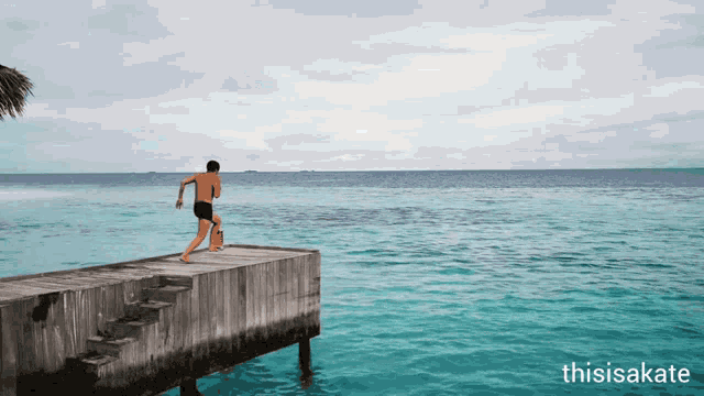 a man in a bathing suit stands on a dock overlooking the ocean with the words thisisakate below him