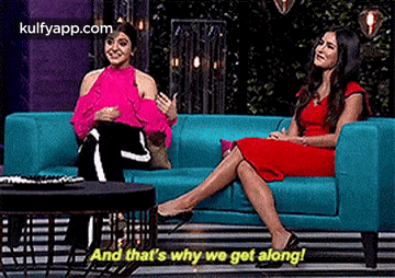 two women are sitting on a blue couch talking to each other and that 's why we get along .