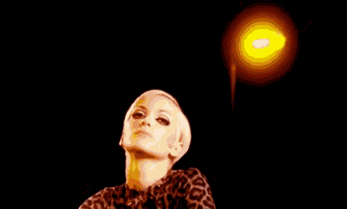 a woman with short blonde hair is sitting in a car wearing a leopard print jacket and gloves .