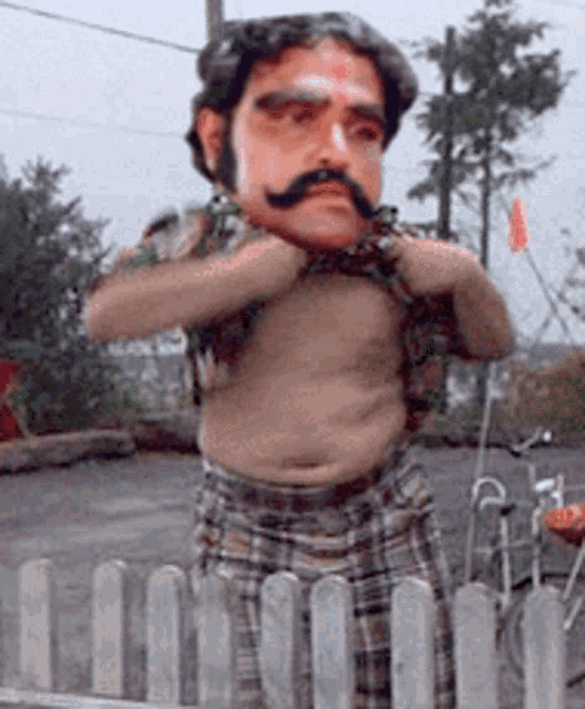a shirtless man with a mustache is standing behind a fence