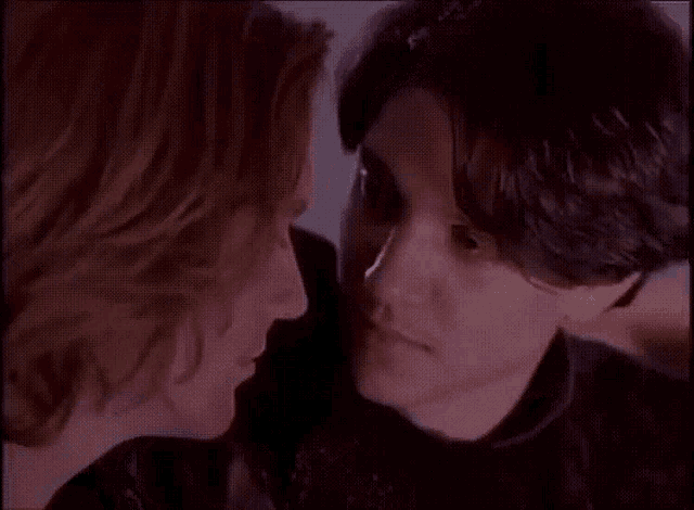 a man and a woman are looking at each other in a dark room