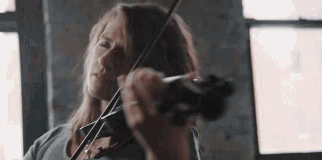 a woman is playing a violin in a dark room .
