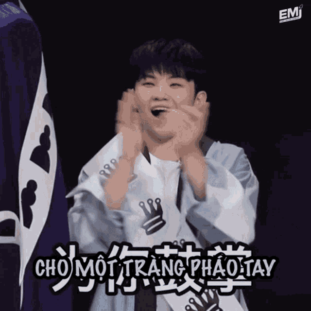 a young man is clapping his hands in front of a sign that reads cho moi trang phao tay