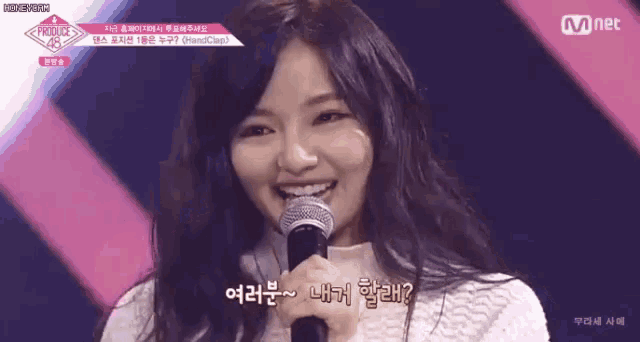 a woman is smiling while holding a microphone and talking into it .