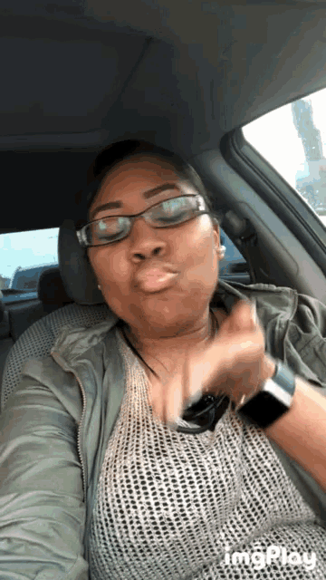 a woman wearing glasses and a watch is blowing a kiss