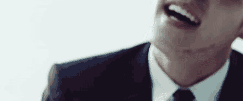 a close up of a man in a suit and tie laughing .