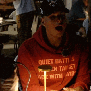 a man wearing a red hoodie that says quiet batti 's