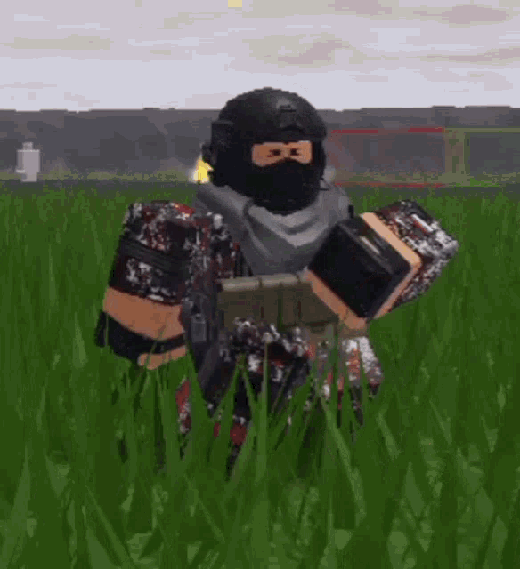a soldier is standing in a field of grass holding a gun .