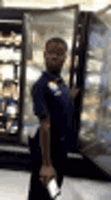 a man in a blue shirt is standing in front of a refrigerator .