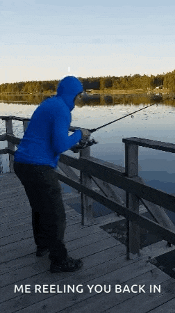 a man in a blue hoodie is fishing on a dock with the words me reeling you back in below him