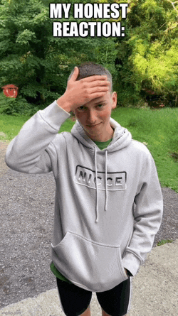 a young man wearing a nice hoodie holds his hand to his head