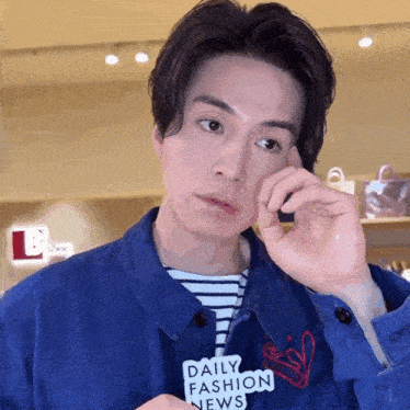 a man wearing a blue jacket has a daily fashion news sticker on his chest