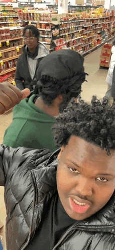 a man in a black jacket is giving a thumbs up in a store
